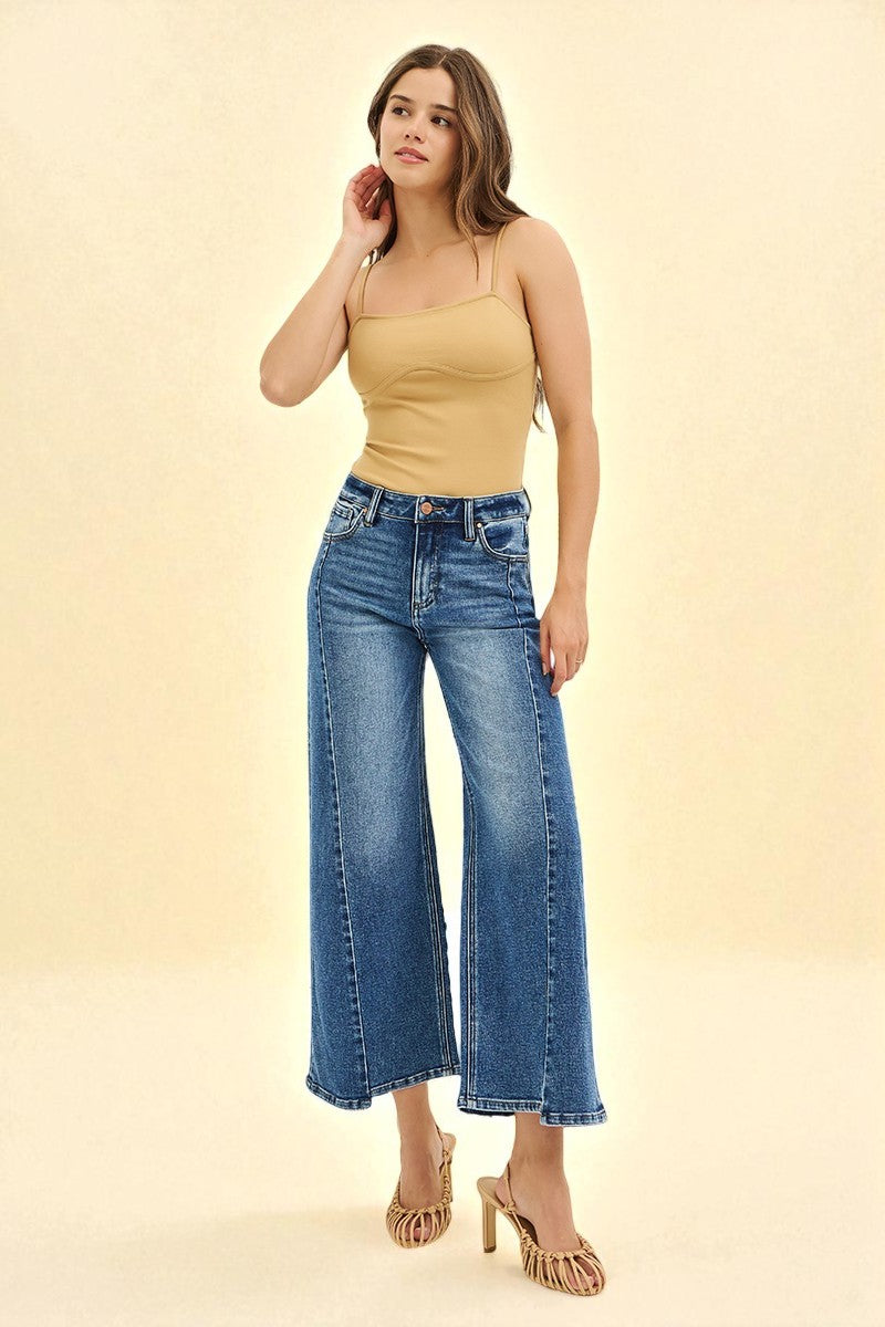 Woman wearing a beige top and blue jeans on a beige background