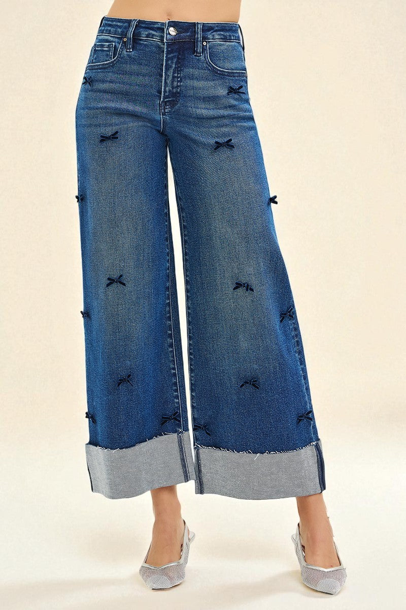 Blue denim wide-leg jeans with distressed details on a beige background