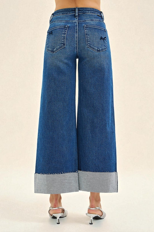 Blue wide-leg jeans with a gray hem on a beige background