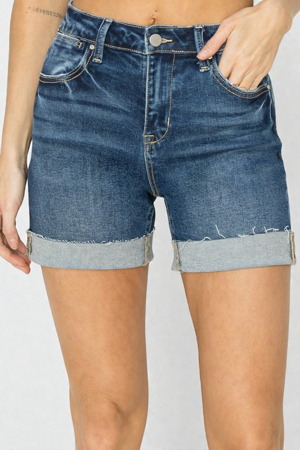 Blue denim shorts worn by a person on a plain background