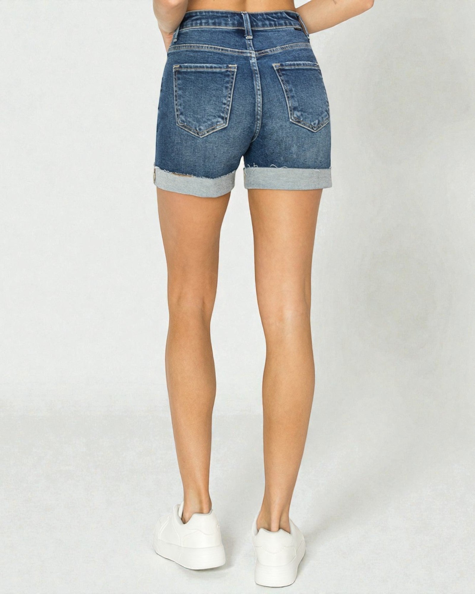 Denim shorts worn by a person on a plain background