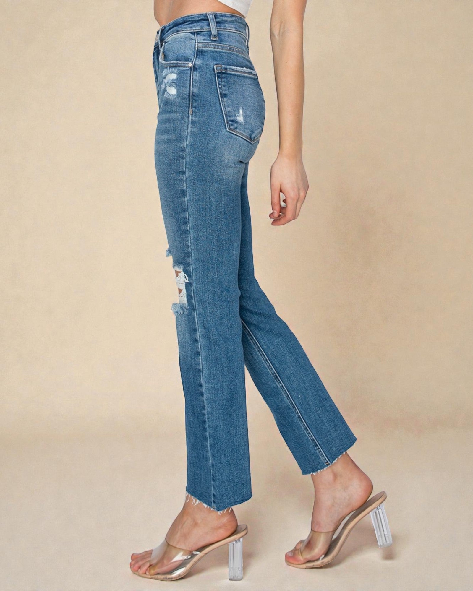 Blue jeans worn by a person on a beige background