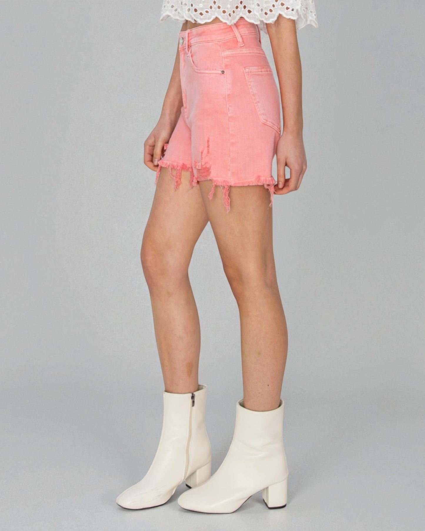 Person wearing a pink denim skirt and white boots on a gray background