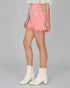Person wearing a pink denim skirt and white boots on a gray background