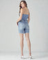 Woman wearing a blue strap top and denim shorts on a white background