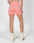 Person wearing pink denim shorts and white boots on a plain background