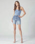 Woman wearing a light blue tank top and denim shorts on a white background