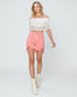 Woman wearing a white lace top and pink shorts on a white background