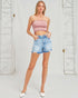 Woman wearing a pink strapless top and denim shorts against a white background