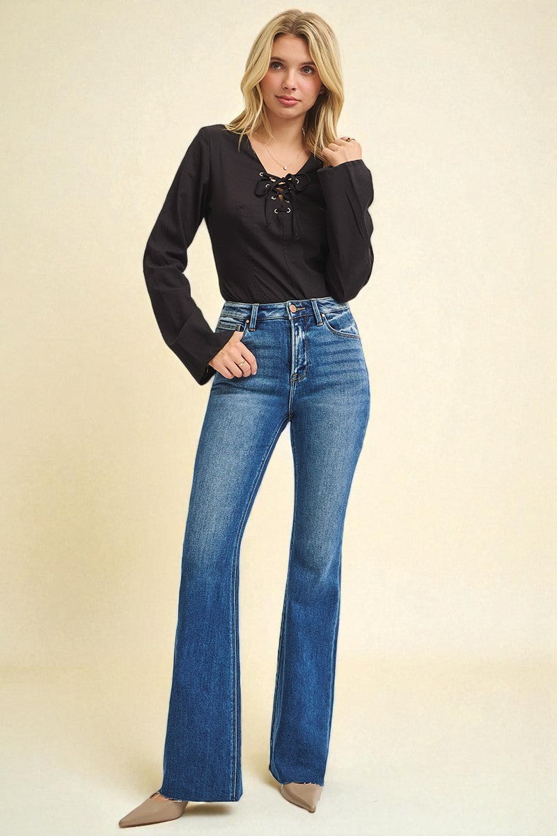 Woman wearing a black top and blue jeans on a beige background