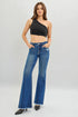 Woman wearing blue jeans and a black one-shoulder top on a white background