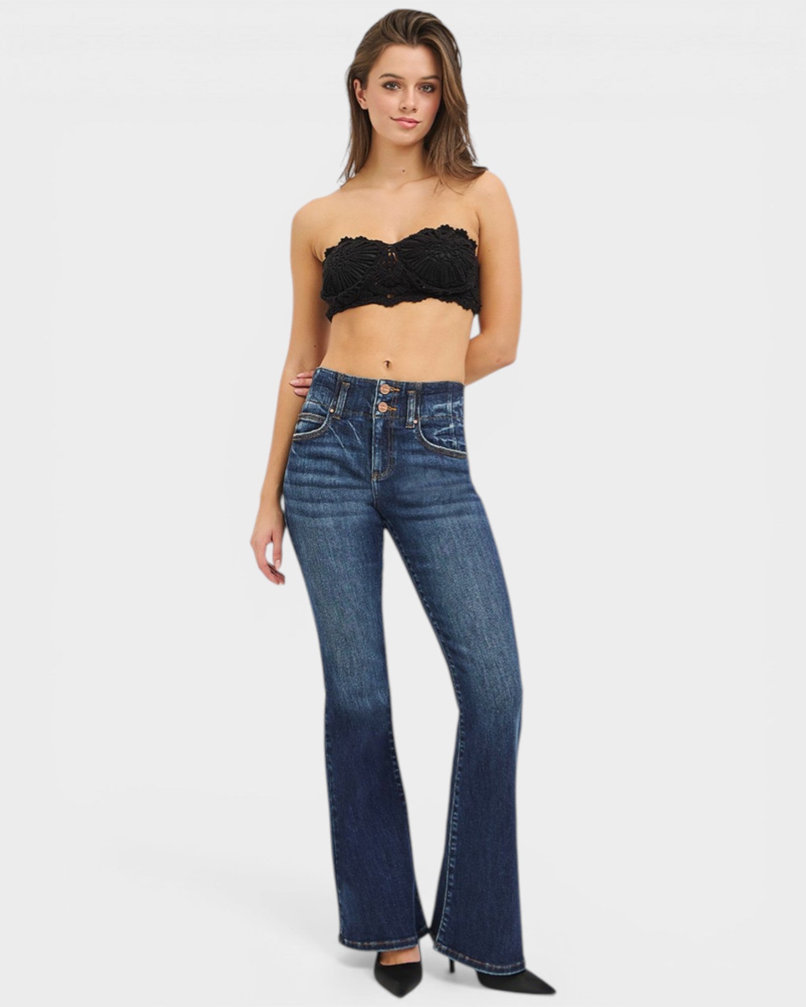 Woman wearing a black strapless top and blue jeans on a white background