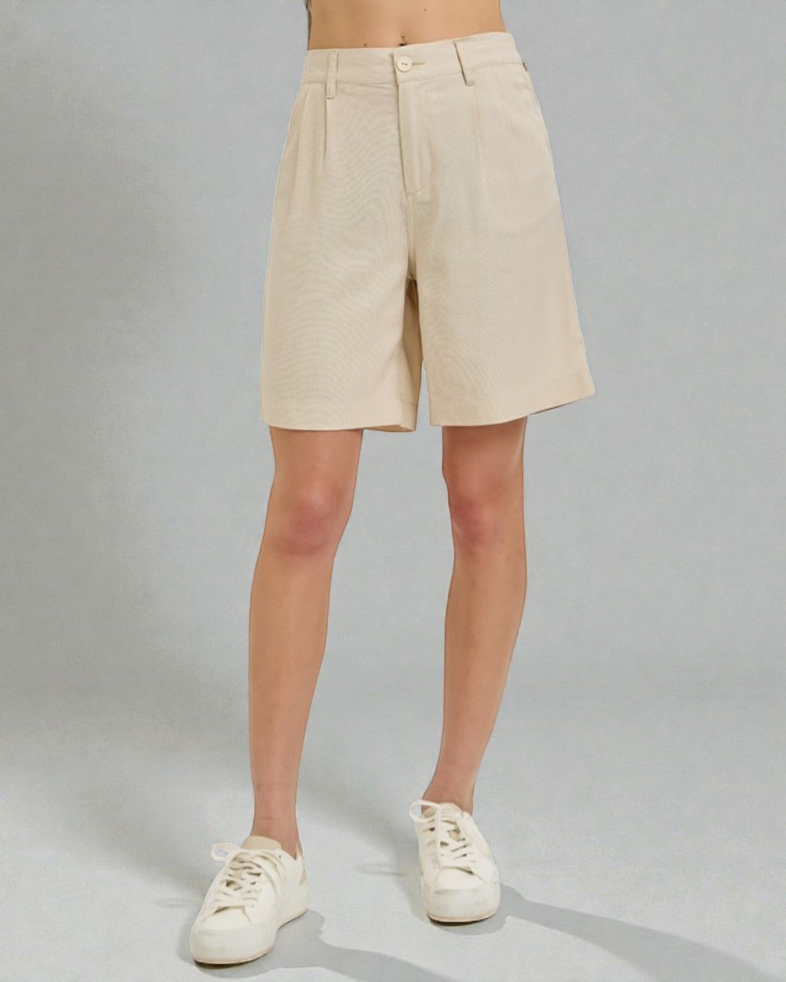 Beige shorts worn by a person on a gray background