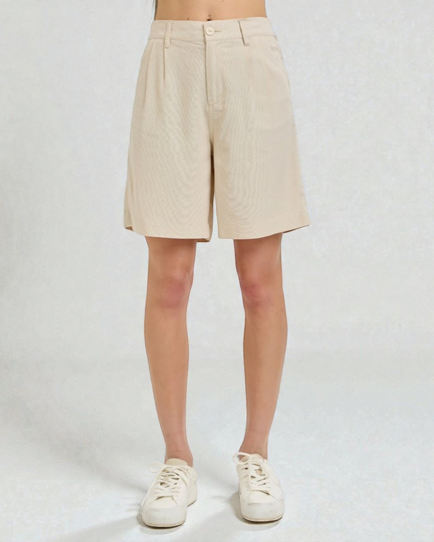 Beige shorts worn by a person on a white background