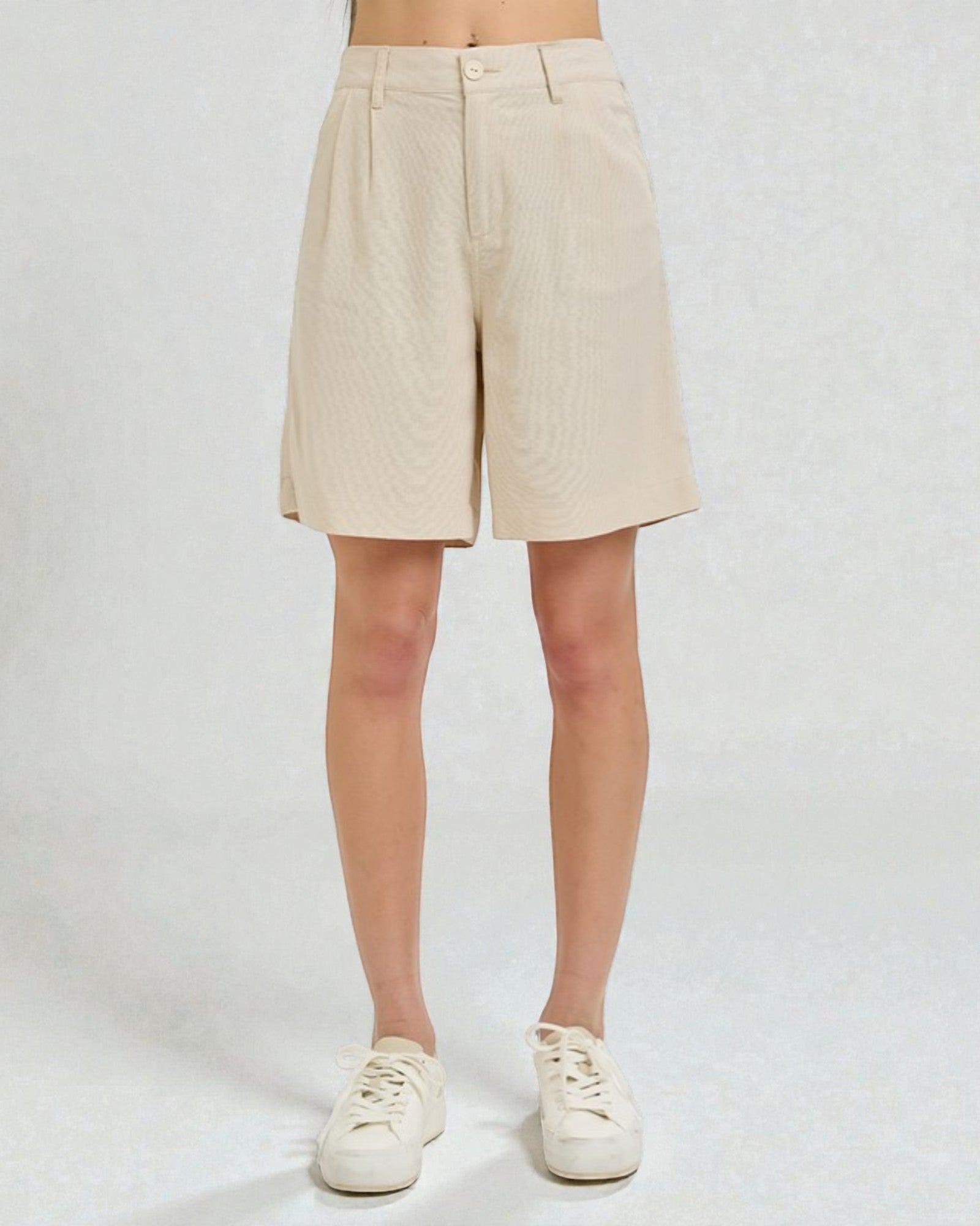 Beige shorts worn by a person on a white background