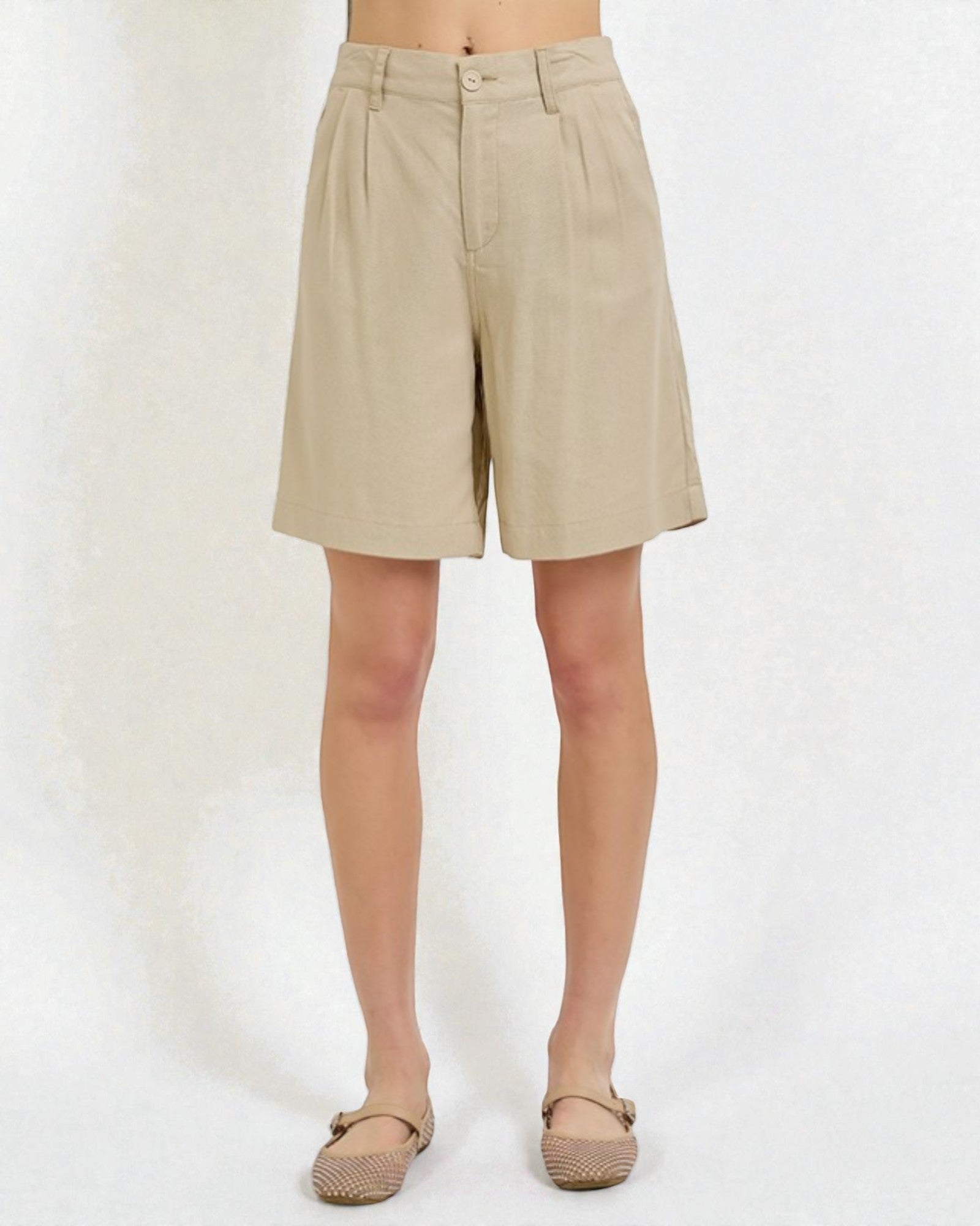 Beige shorts worn by a person on a white background