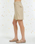 Beige shorts worn by a person on a light gray background with small decorative elements.