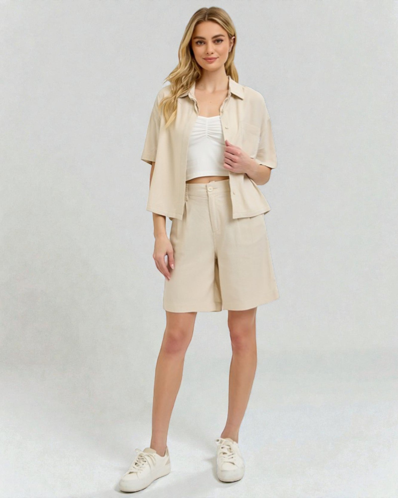 Woman wearing a beige outfit with shorts and a jacket on a white background