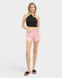 Woman wearing a black halter top and pink shorts on a white background
