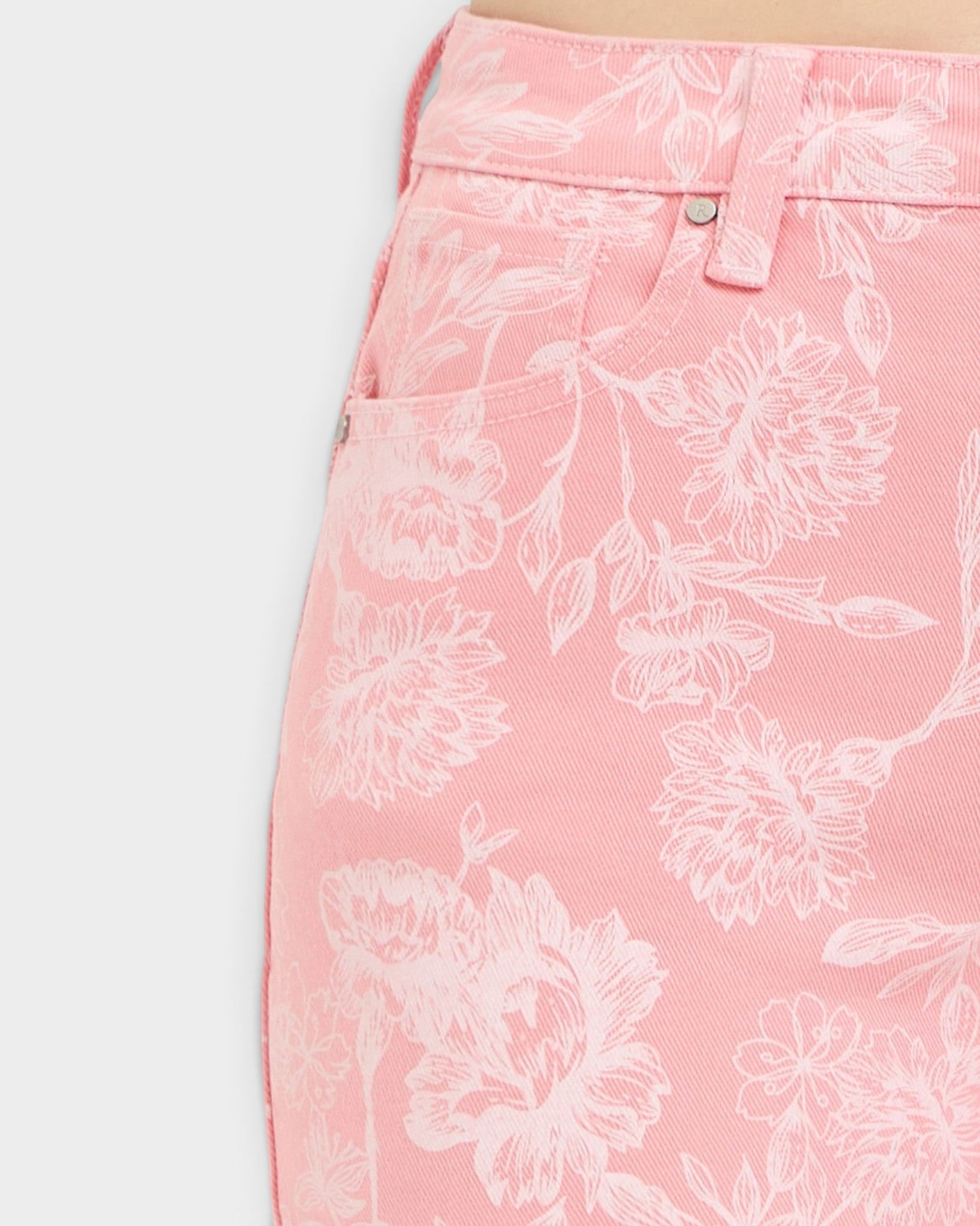 Close-up of pink shorts with white floral pattern on a white background