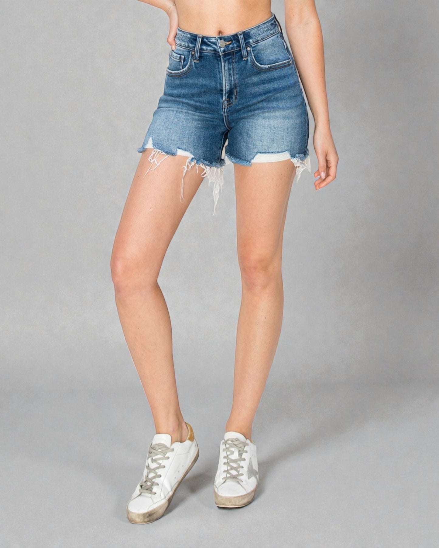 Person wearing denim shorts on a gray background