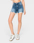 A model wearing high-waisted, frayed-hem blue denim shorts and white sneakers, shown from the waist down on a light gray studio background.