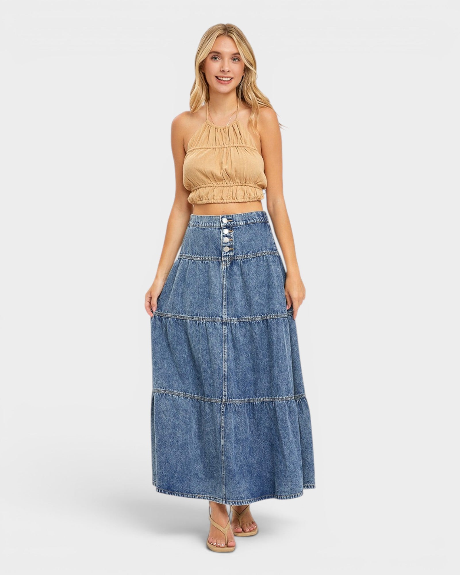 Woman wearing a beige top and blue denim skirt on a white background