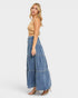 Woman wearing a beige top and blue denim wide-leg pants on a white background
