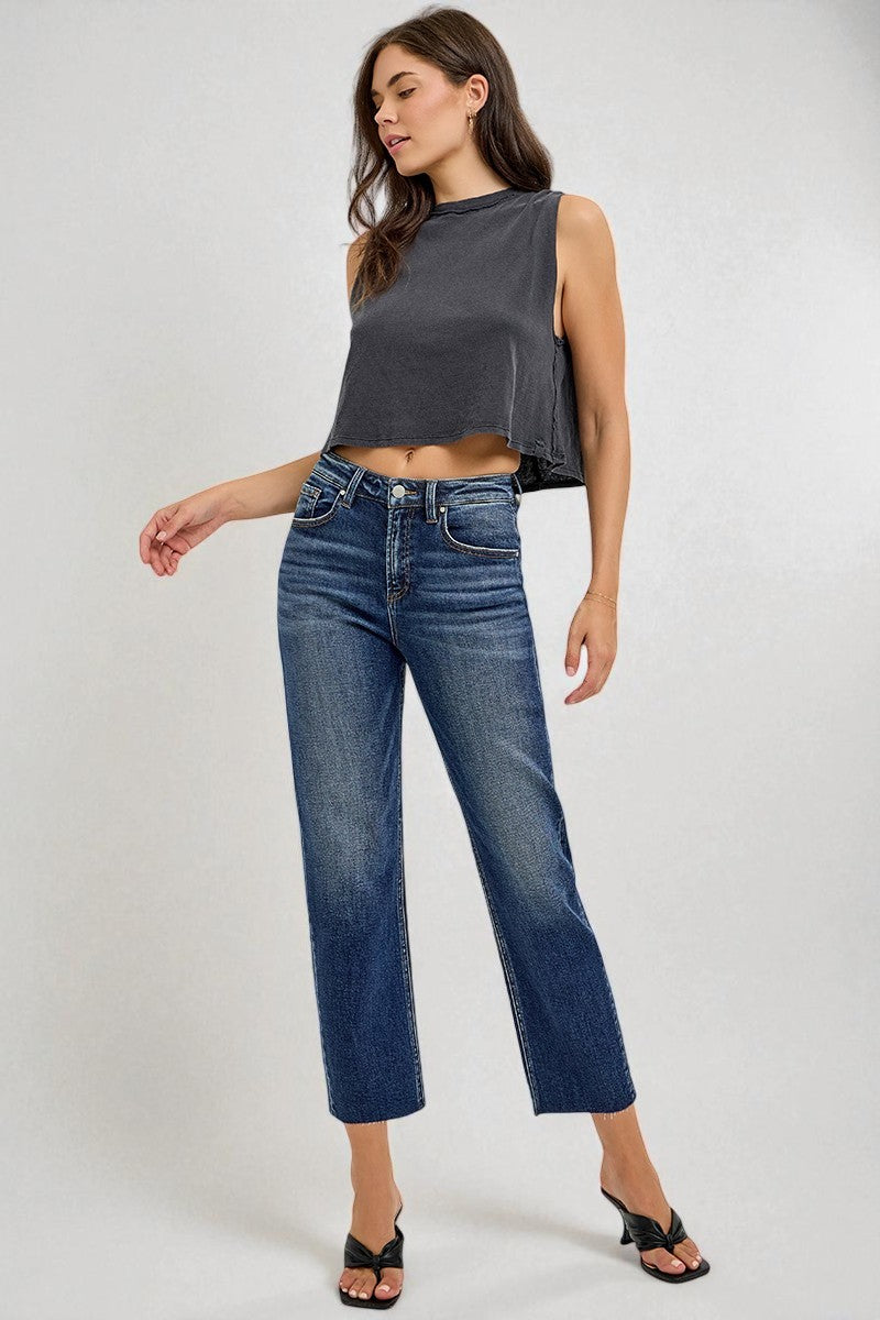 Woman wearing a dark gray sleeveless top and blue jeans on a white background