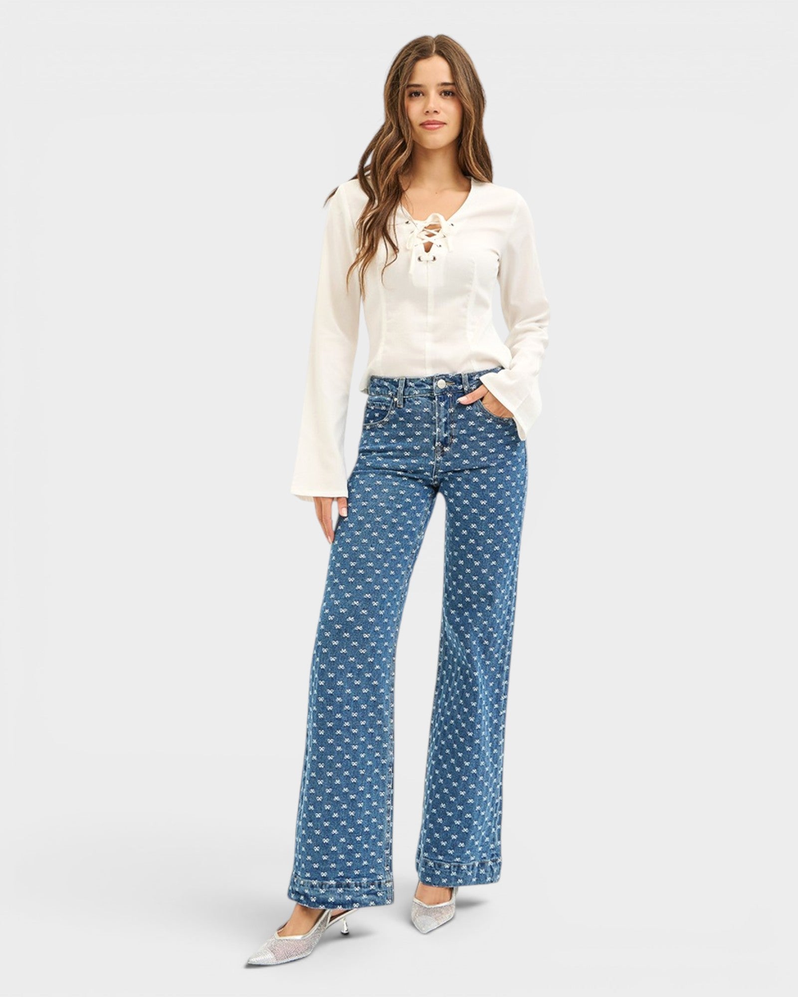 Woman wearing a white blouse and blue polka dot pants on a white background