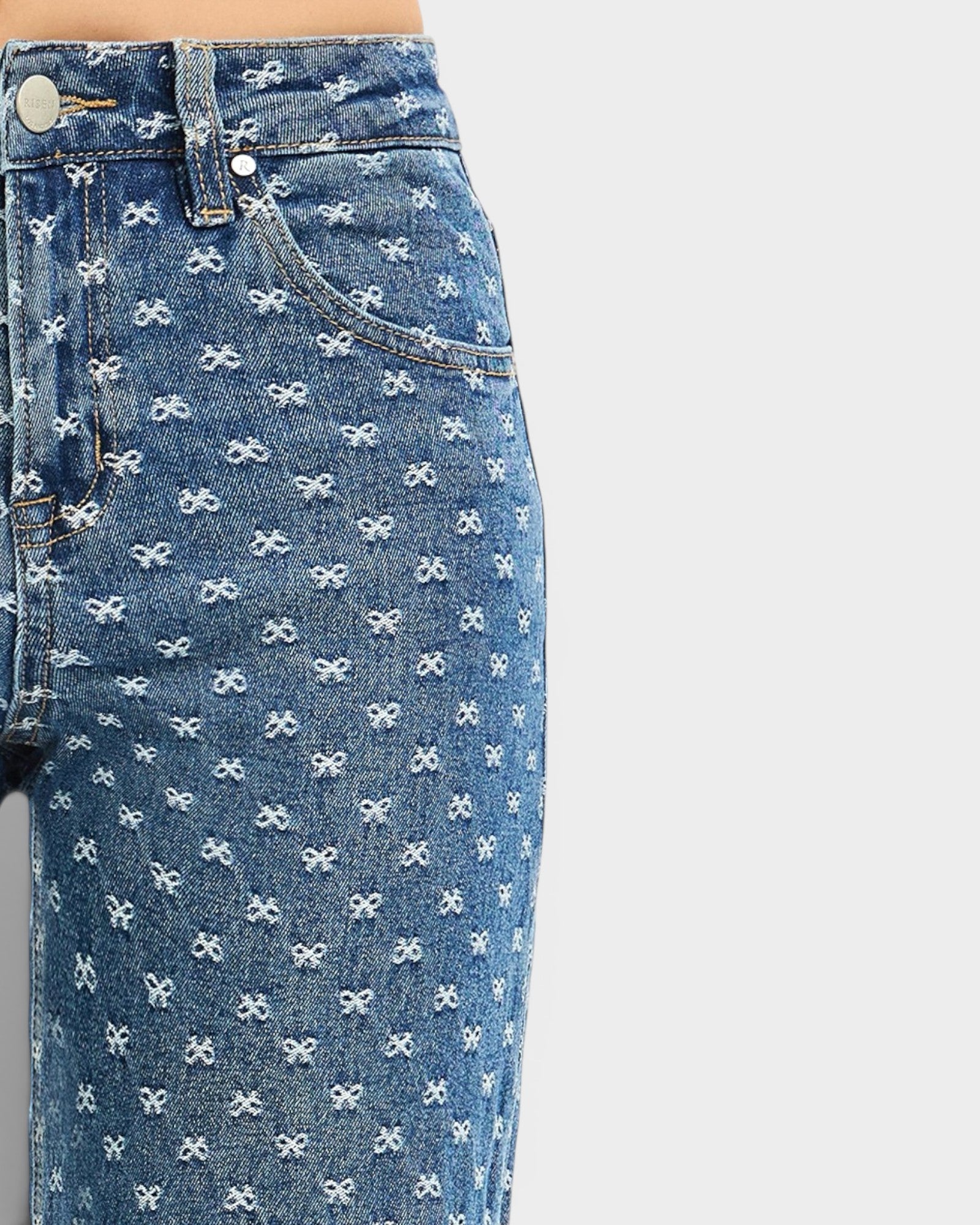 Blue jeans with white bow pattern on a light gray background