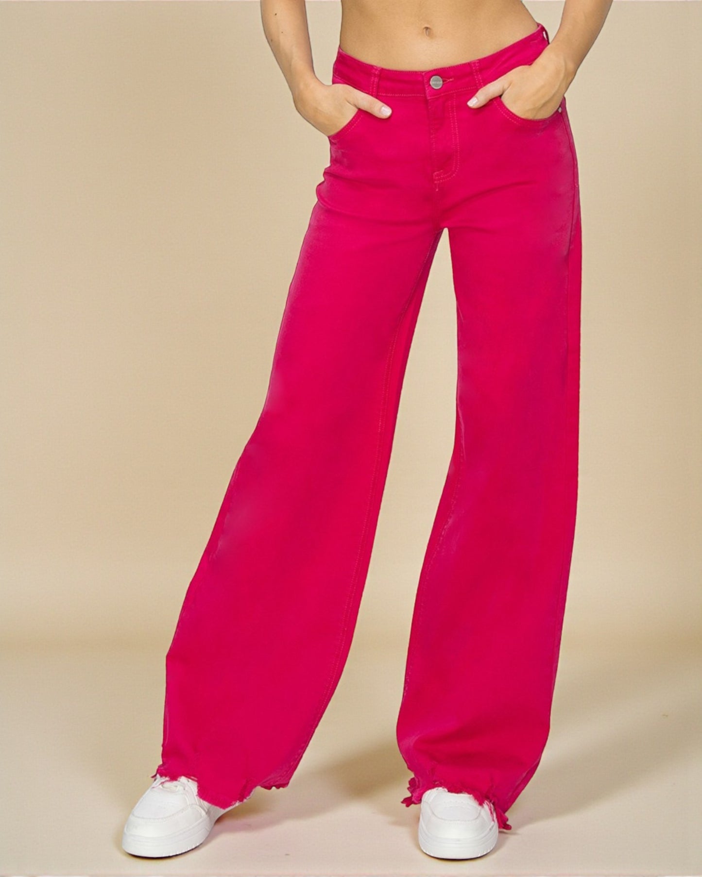 Person wearing bright pink wide-leg jeans on a beige background