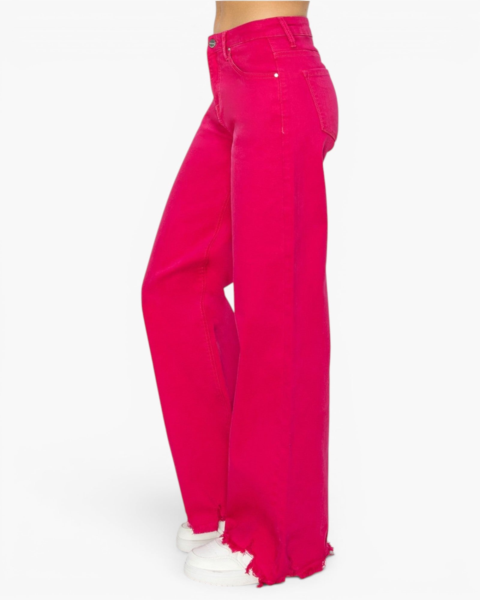Bright pink wide-leg denim jeans shown on a model from the side, featuring raw, frayed hems and white sneakers against a plain white background.