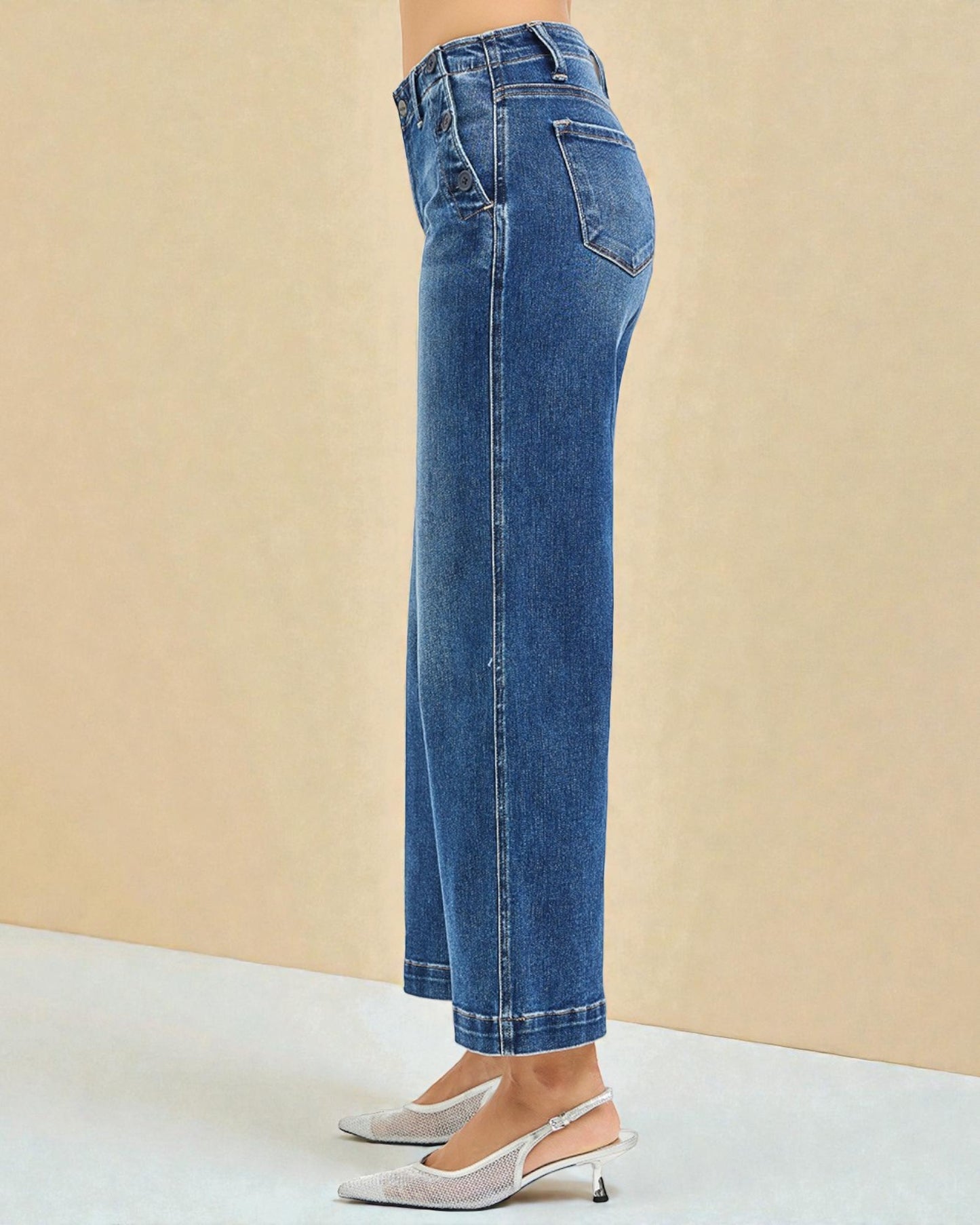 Blue jeans worn by a person on a beige background