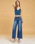 Woman wearing a blue top and jeans against a beige background