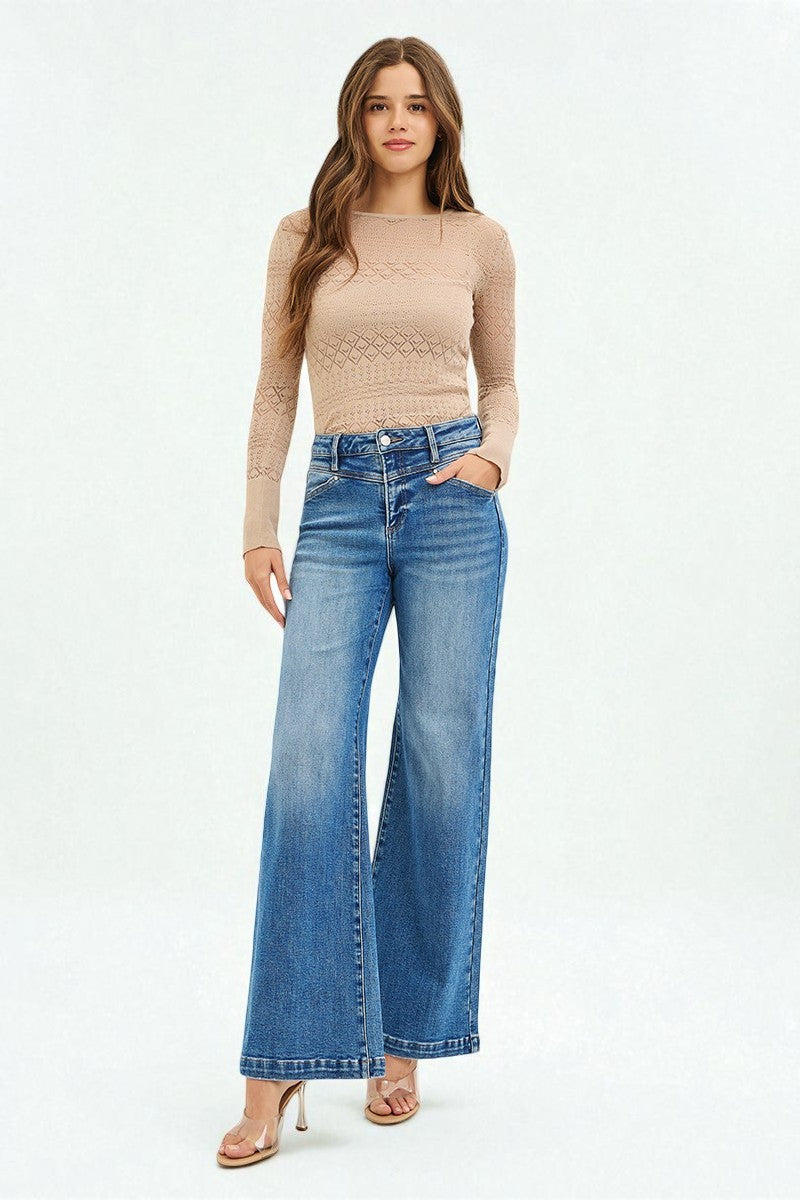 Woman wearing a beige long-sleeve top and blue jeans on a white background