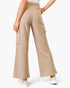 A model is shown from the waist down wearing beige wide-leg cargo pants with side flap pockets, paired with white sneakers against a light gray studio background.
