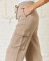 Beige cargo pants worn by a person against a white brick wall.