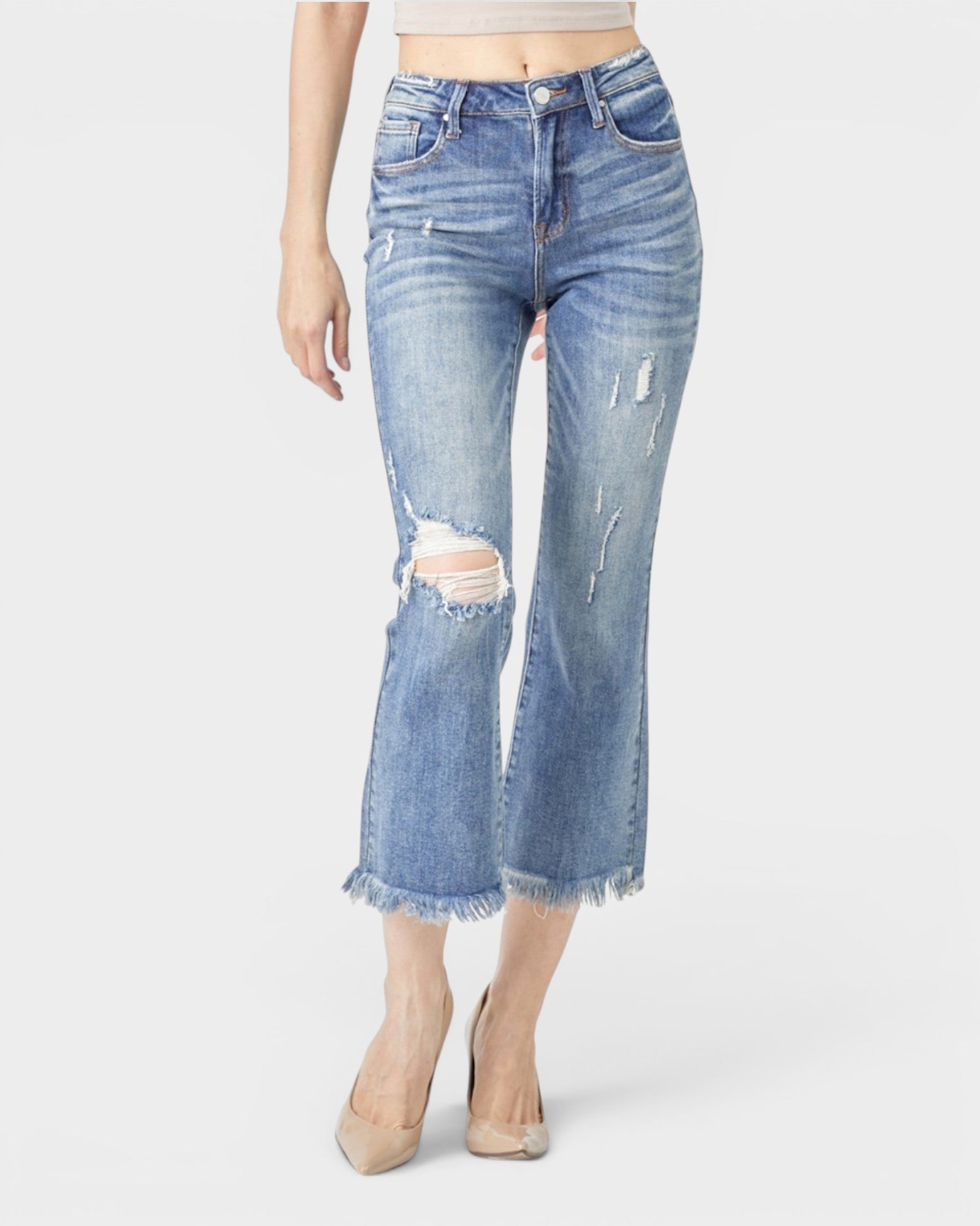 Distressed blue jeans worn by a person on a white background