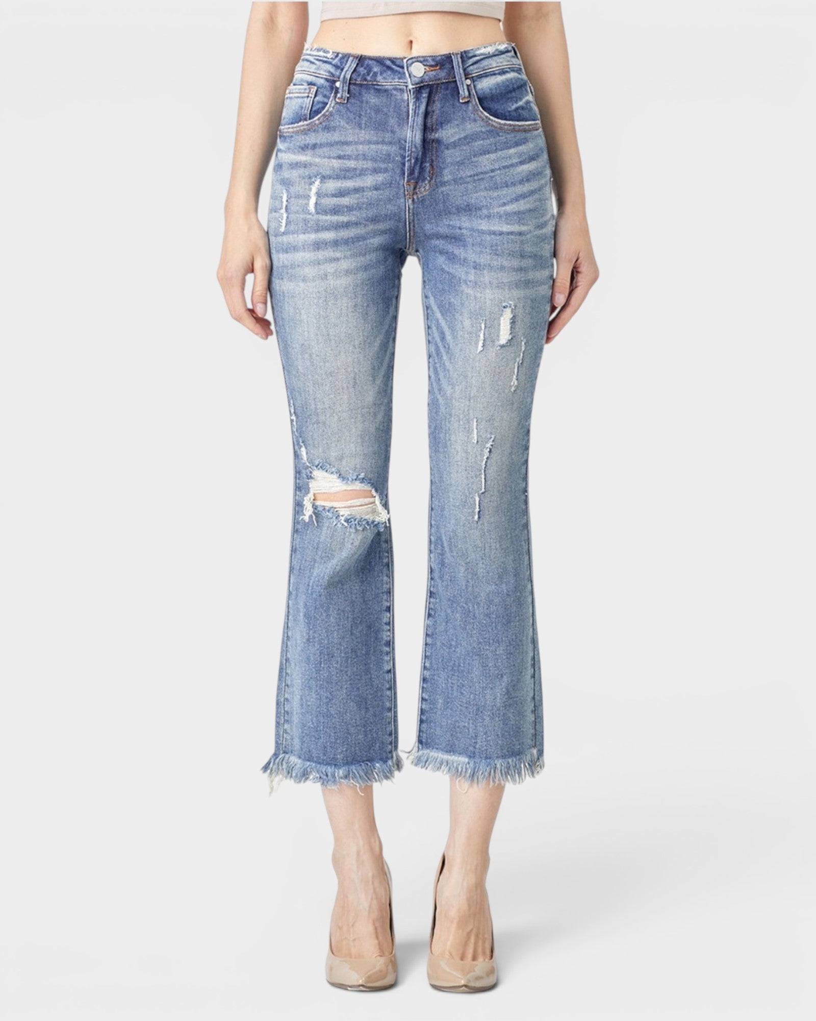 Person wearing distressed blue jeans on a white background
