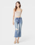 Woman wearing a beige strapless top and distressed blue jeans on a white background