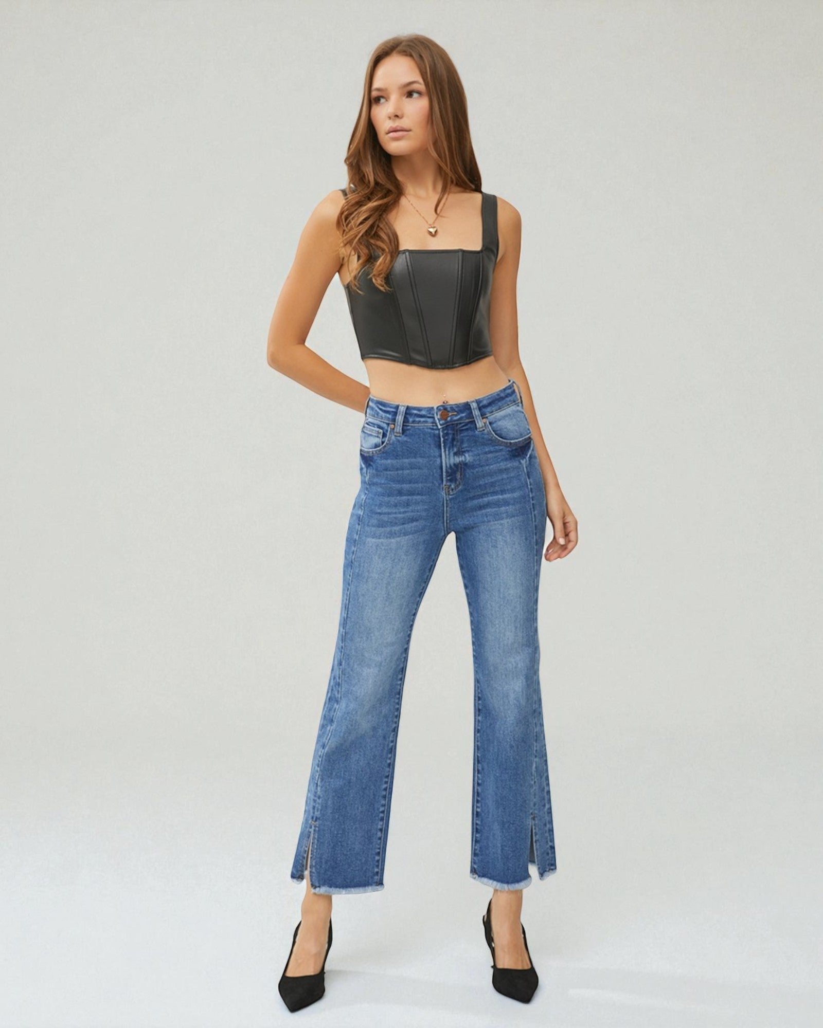 Woman wearing a black leather top and blue jeans on a white background