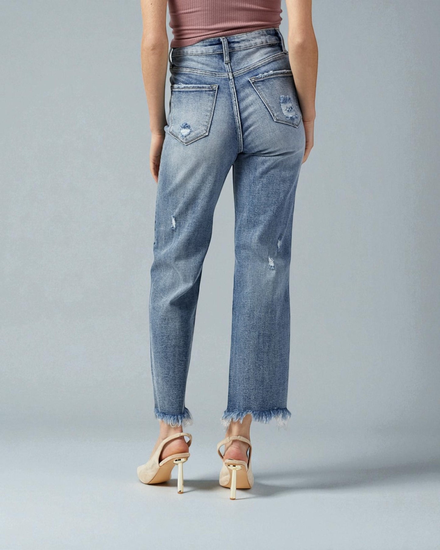 Person wearing light blue distressed jeans on a gray background