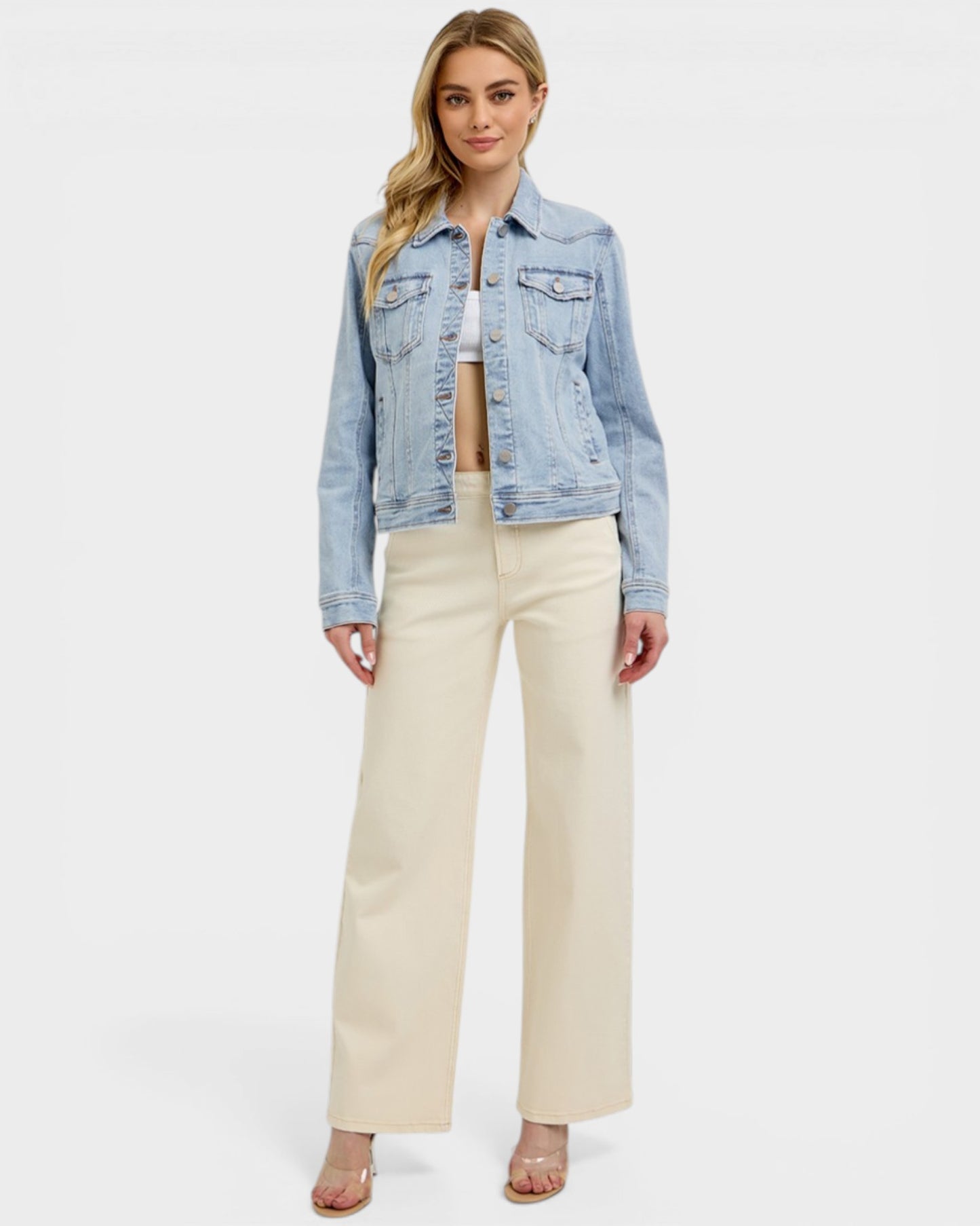 Woman wearing a denim jacket and beige pants on a white background