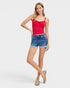 Woman wearing a red tank top and blue denim shorts on a white background