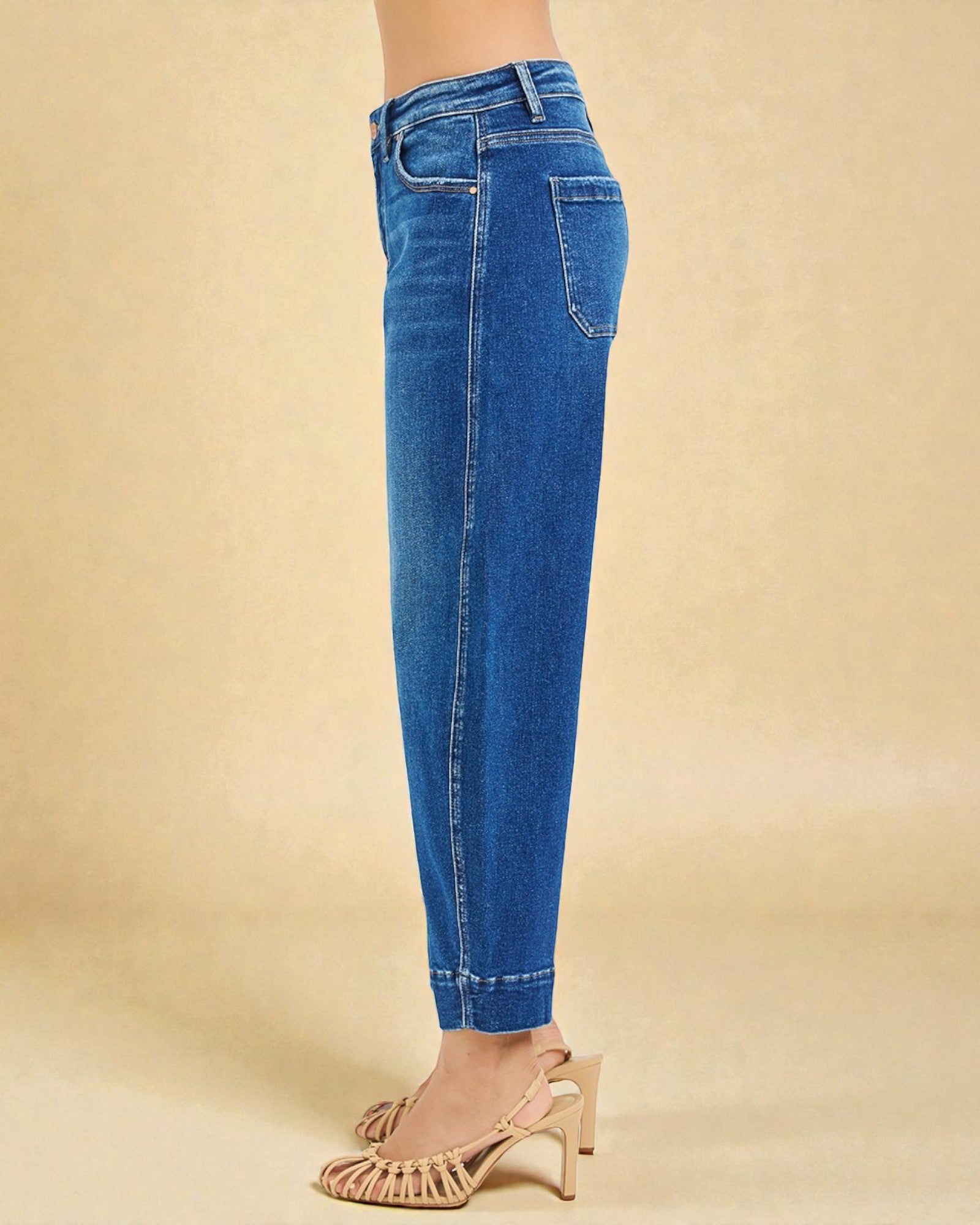 Blue jeans worn by a person on a beige background