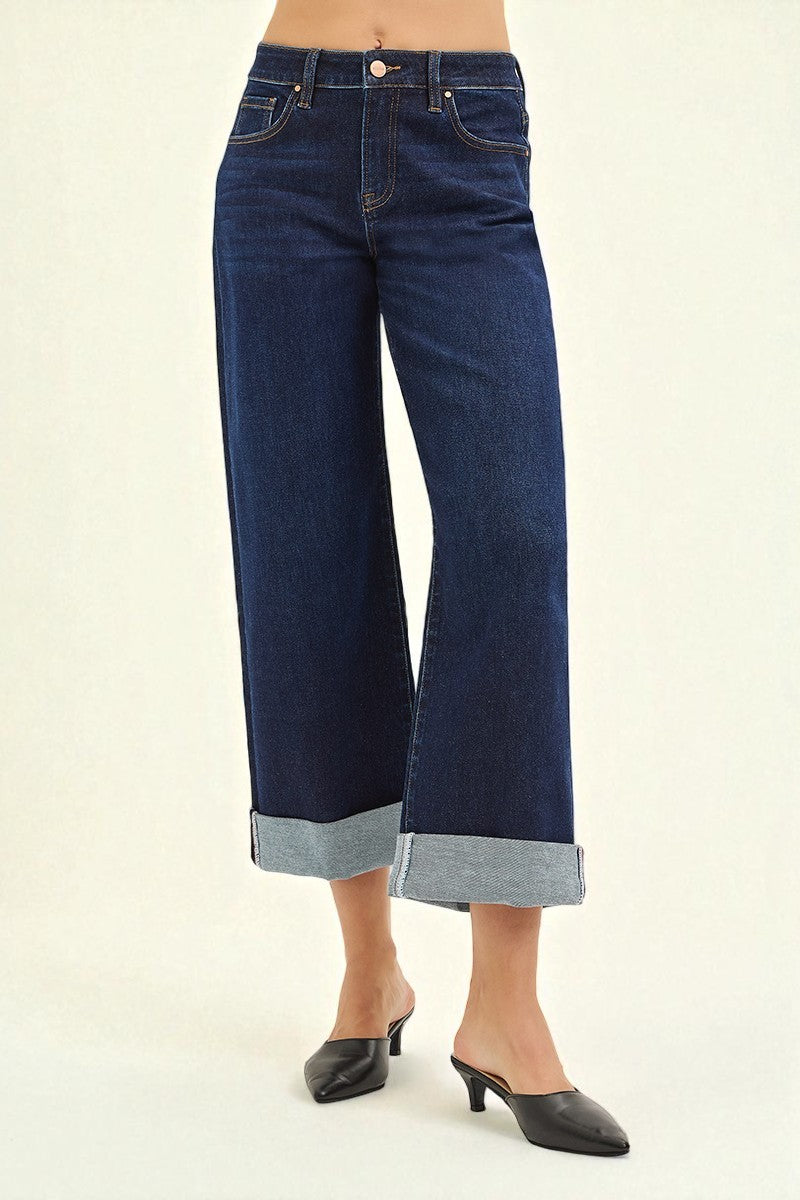 Dark blue wide-leg jeans worn by a person on a beige background