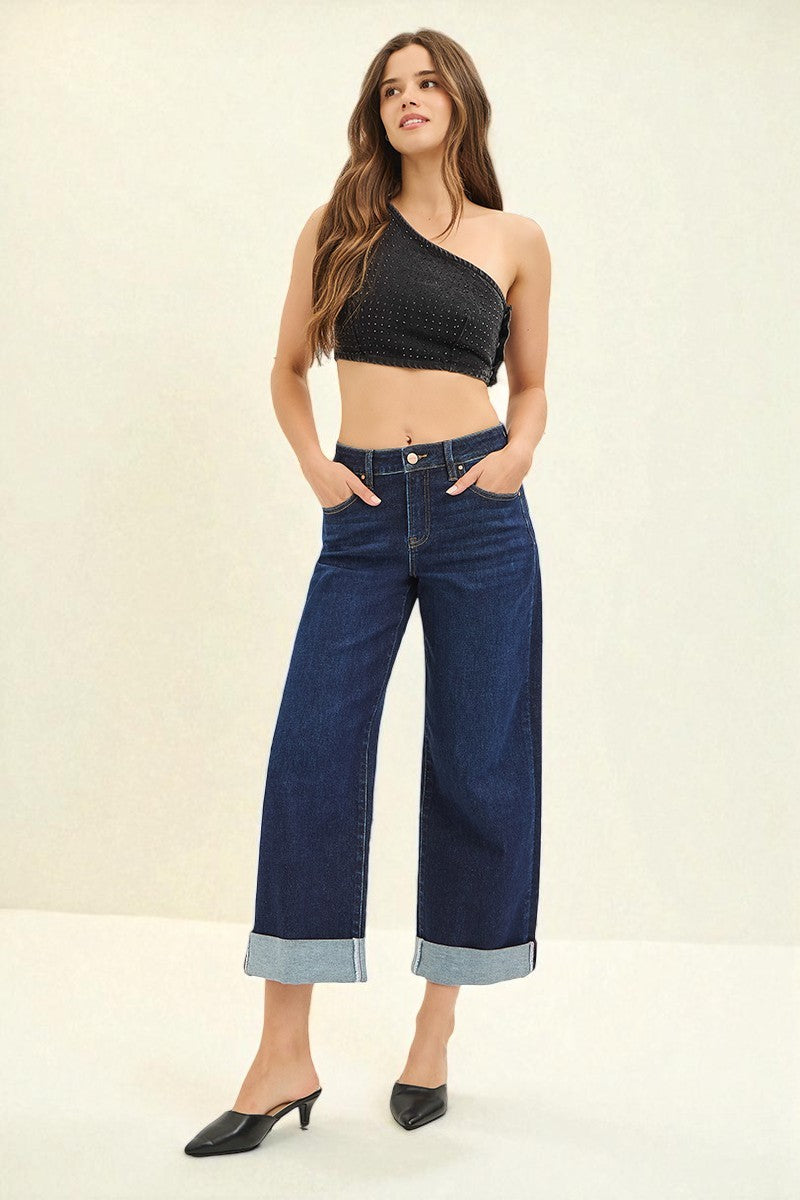 Woman wearing a black crop top and blue jeans on a plain background
