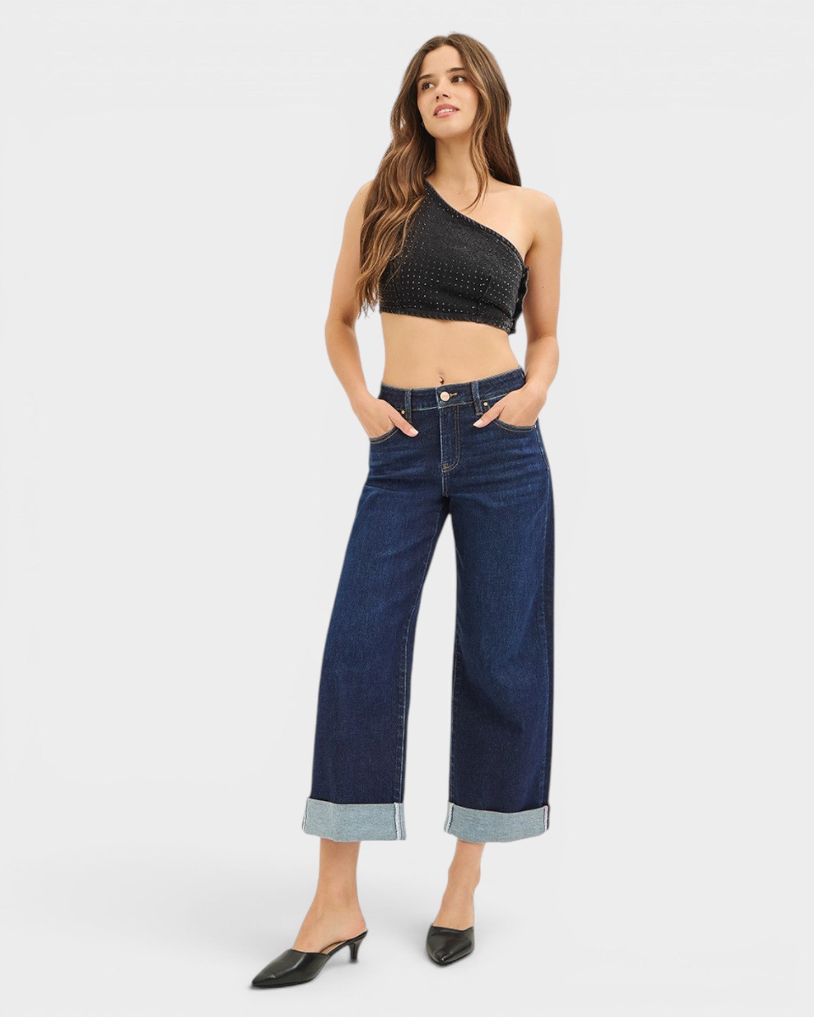 Woman wearing a black crop top and blue jeans on a white background