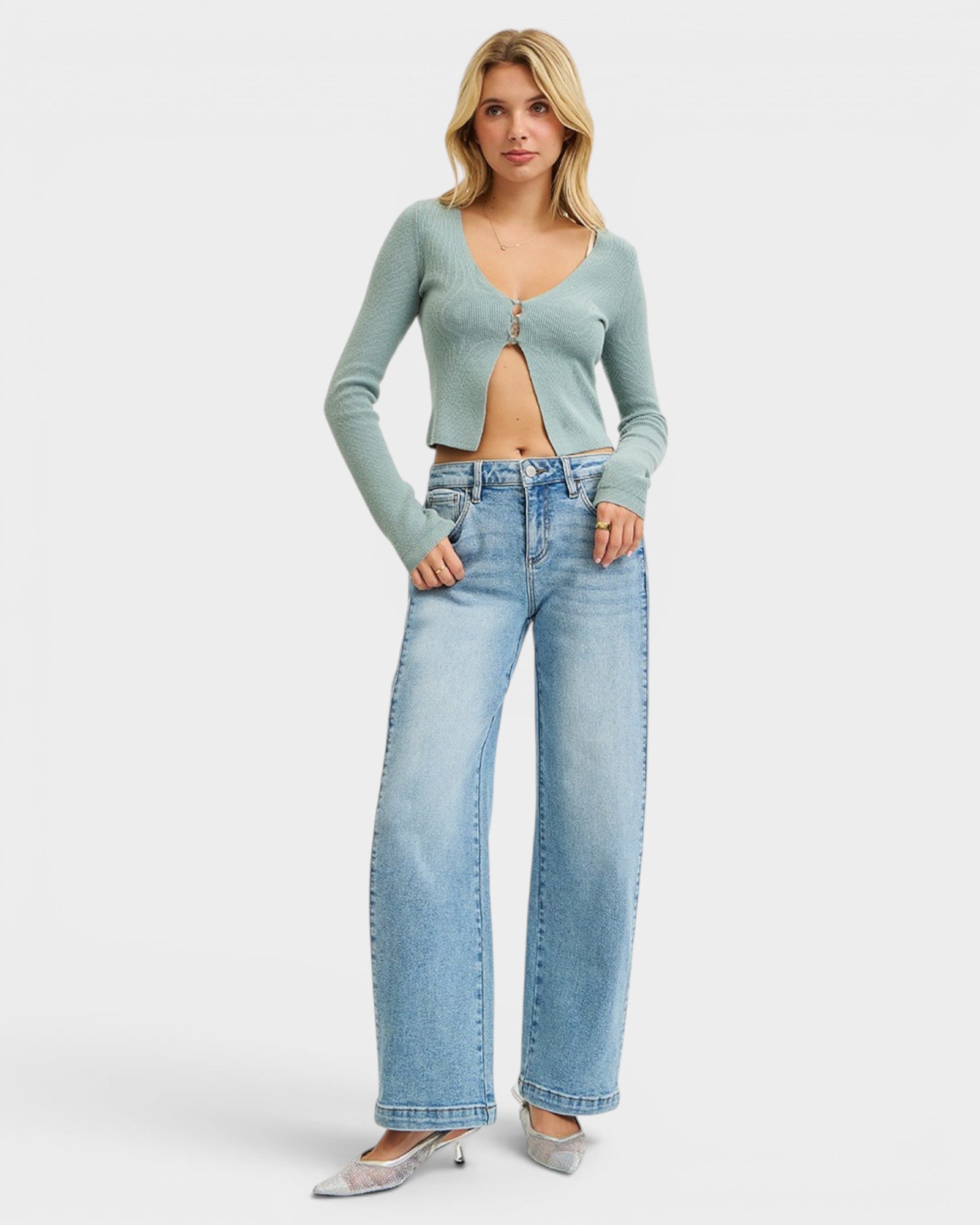 Woman wearing a light blue cardigan and jeans on a white background